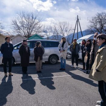 日本包車旅遊車內情境，專業司機與後座旅客交流互動，體現包車服務讓旅客放鬆享受旅程、無需分心駕駛的核心價值